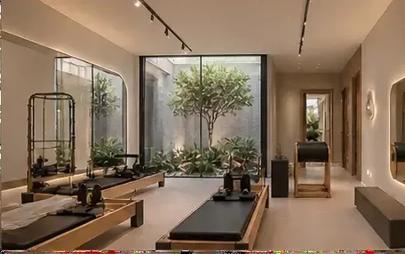 Sala de Pilates equipada com reformers de madeira e vista para jardim interno