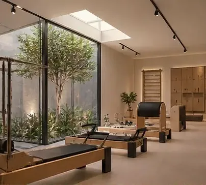 Sala de Pilates iluminada por claraboia com equipamentos clínicos e plantas